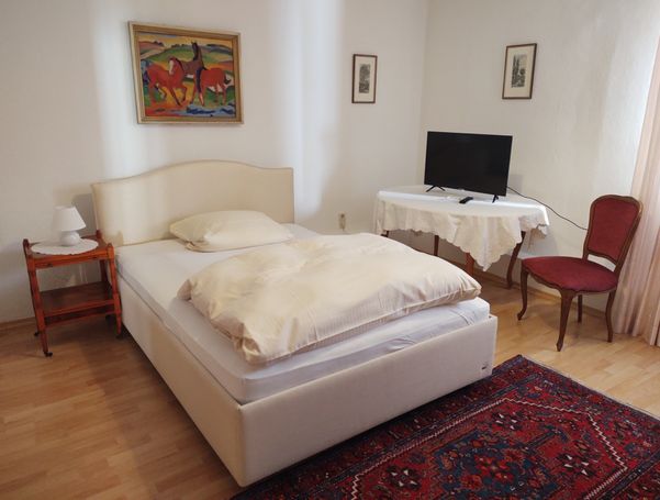 Bett mit Nachtkästchen, TV auf separatem Tisch, Ölgemälde "Rote Pferde". 
